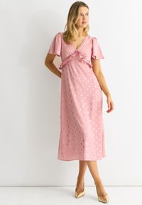 Pink midi dress with ruffled v-neckline and short puff sleeves. Features gold polka dots, made from a smooth, lightweight fabric.
