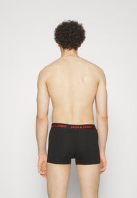 Schwarze Baumwollunterhose mit rotem, markiertem Bund. Sie verfügt über einen körpernahen Schnitt und eine glatte Textur, die für Komfort und minimale Sichtbarkeit sorgt.