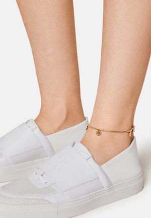 Witte instapsneakers met een soepel leren bovenwerk, een gestructureerd grijs paneel en een dikke zool. Gouden enkelband met ronde bedels.