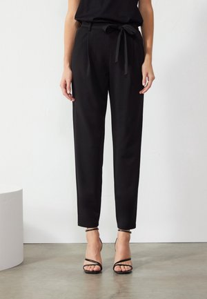 Zwarte gepersonaliseerde broeken met een hoge taille, verstelbare strikriem en tapered fit. Glad materiaal met voorplooien en enkel-lengte ontwerp.