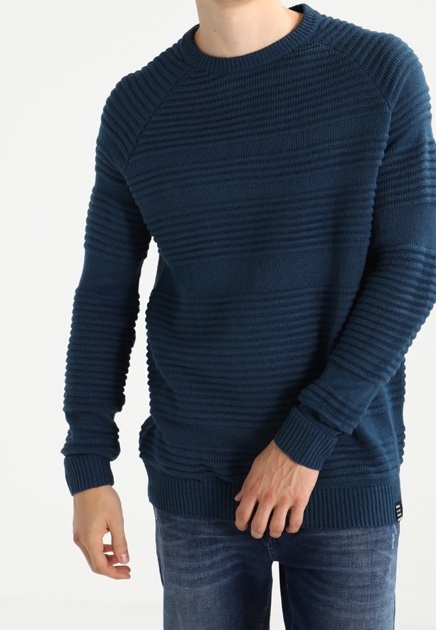 Dunkelblauer Pullover mit strukturierten horizontalen Streifen, Rundhalsausschnitt und gerippten Bündchen und Saum. Tragen mit hellblauen Jeans.