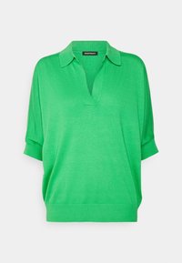 Polo shirt verde a maniche corte in un morbido materiale a maglia, con collo a V e colletto a ribattuto. Texture liscia con vestibilità comoda.