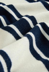 Tissu doux avec des rayures horizontales bleu marine et blanches, montrant un gros plan de sa surface texturée et pelucheuse.