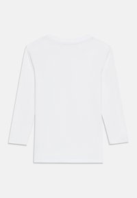 Λευκό μακρυμάνικο μπλουζάκι με στρογγυλή λαιμόκοψη. Ομαλή υφή χωρίς ορατά σχέδια ή μοτίβα. Οπίσθια όψη χωρίς επιπλέον λεπτομέρειες.