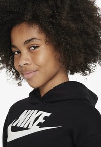 Black hoodie made of soft fabric with a large white "NIKE" logo and swoosh design. Features a drawstring hood and textured curls.