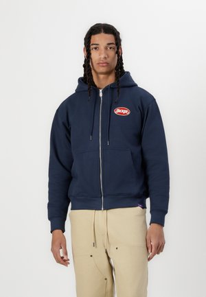 Kapuzenjacke in Marineblau mit Reißverschluss, aus Baumwollmischung, mit einer vorderen Kängurutasche und rotem, gesticktem "HACKER"-Logo auf der Brust.