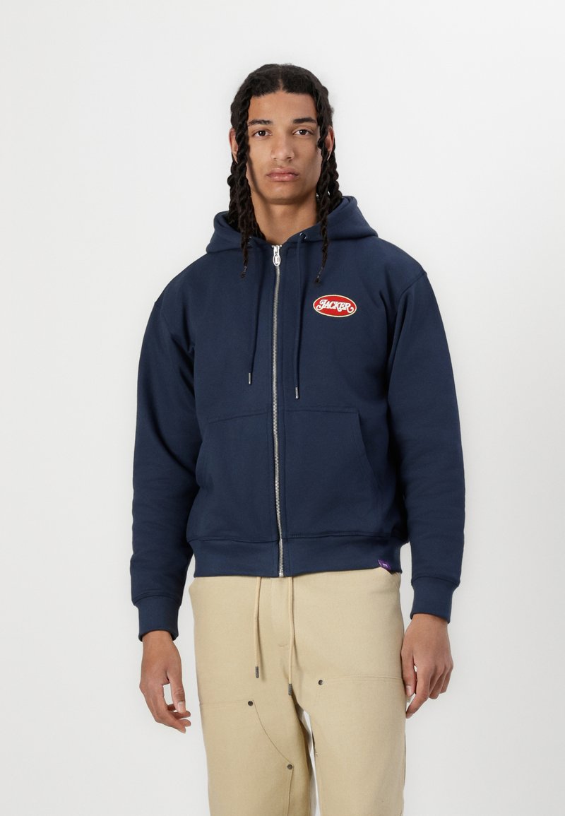 Mörkblå dragkedja hoodie i bomullsblandning, med en kanguroficka fram och röd broderad "HACKER"-logga på bröstet.