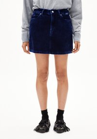Navy corduroy mini-jongensrok met een ontwerp met vijf zakken, riemlussen en een knoopsluiting aan de voorkant. Zachte textuur met zichtbare ribbelstructuur.