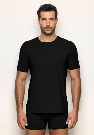 Svart kortärmad t-shirt i ribbad väv med rund halsringning, tillsammans med svarta tighta shorts. Slät textur och enkelt design.