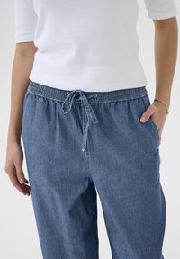 Lyseblå denimbukser med elastisk talje og snor, med sidelommer og en afslappet pasform. Glat tekstur, afslappet design.