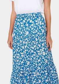 Fustă cu imprimeu floral albastru și flori albe, talie elastică, tiv cu volane în straturi, până la genunchi, fabricată dintr-un material ușor.
