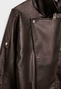 Ciemnobrązowa skórzana kurtka o wyraźnej fakturze ziarna, z ukośnym zamkiem, zatrzaskami na ramieniu i detalem w postaci przedniej klapy.