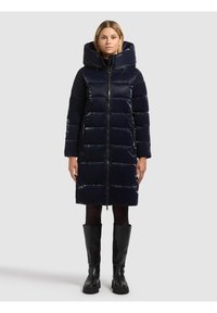 Mornarsko plava prozračna jakna s visokim ovratnikom i velikim kapuljačom, središnjim patentnim zatvaračem i dva bočna džepa. Izrađena od sjajnog, izoliranog materijala.