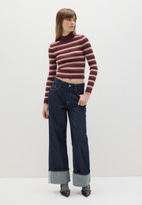 Top corto de manga larga a rayas burdeos y crema combinado con pantalones de mezclilla de pierna ancha de tiro alto en un tono oscuro, con un dobladillo doblado de color azul claro.