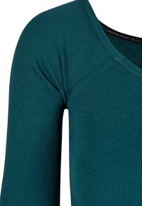Tealfärgad ribbad långärmad topp med v-ringad hals och subtil textur. Tyget verkar mjukt med en lätt stretch.