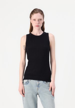 Svart ribbet tropsløse topp med rund hals, med en tettsittende design. Kombinert med lyseblå, avslappede jeans.