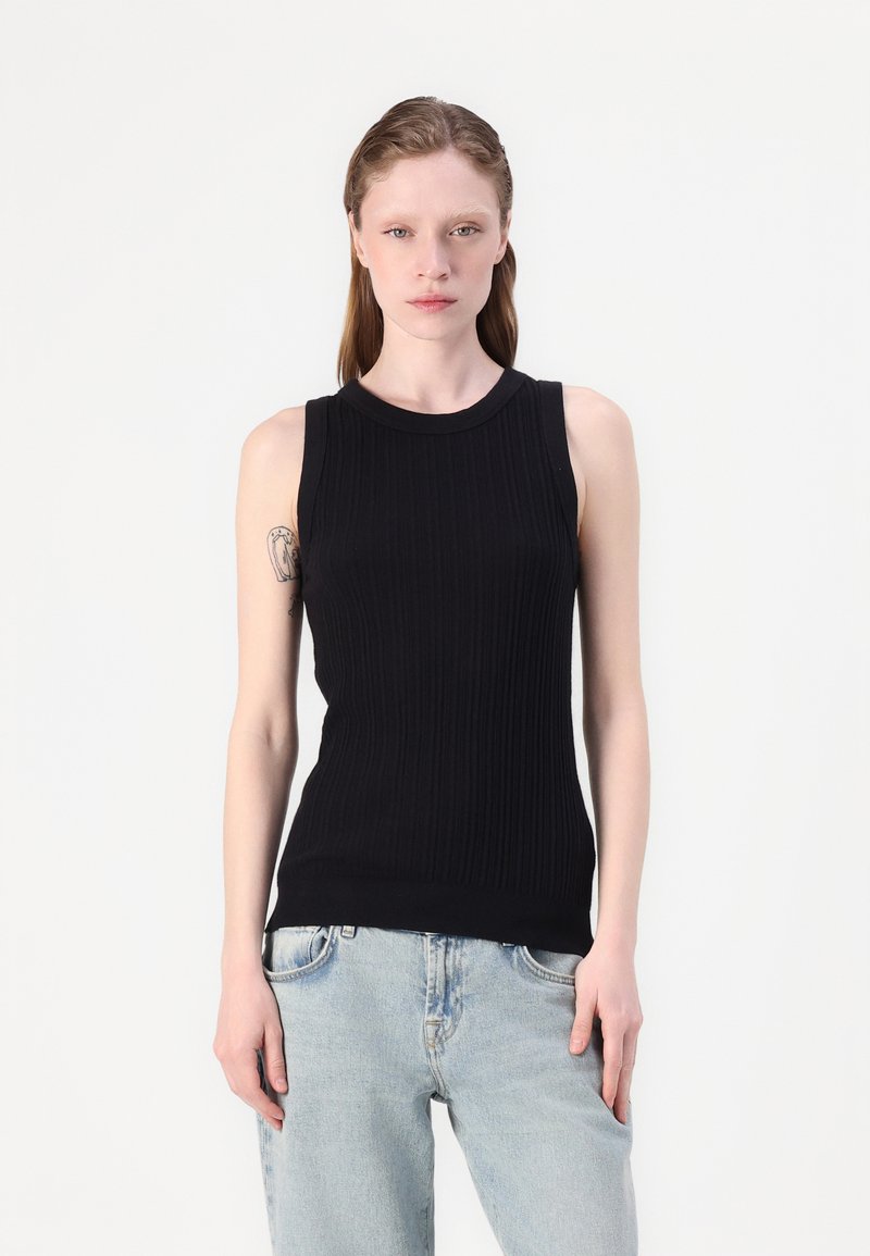 Svart ribbet tropsløse topp med rund hals, med en tettsittende design. Kombinert med lyseblå, avslappede jeans.