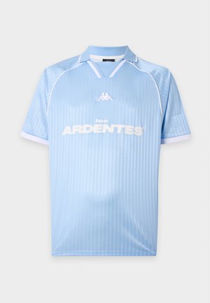 Lichtblauw sportshirt met korte mouwen, witte kraagafwerking, wit logo midden op de borst en tekst "les ARDENTES" op de voorkant.