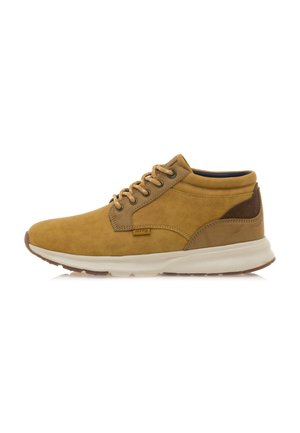Stivali alla caviglia in suede beige con dettagli in pelle marrone sul tacco, punta rotonda e suola in gomma beige. Caratterizzati da lacci beige e dettagli di cucitura minimal.