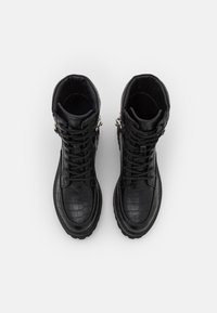 Botas altas negras de piel de cocodrilo, con cordones, herrajes plateados en los laterales y una suela robusta.