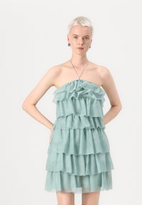 Strapless lagerdraperad klänning tillverkad av genomskinlig mintgröna tyg, med flera volanger av varierande längd och en figurnära bodice med elastisk halsringning.