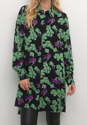 Camisa negra con patrón floral en verde y púrpura, de mangas largas, diseño de botones y un corte holgado. Tejido texturizado.