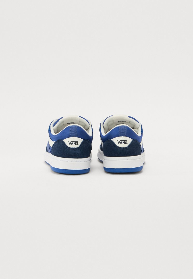 Baskets Vans bleues en suédine et tissu, dotées d'une semelle en caoutchouc blanc et d'un col rembourré. Marquage à l'arrière.