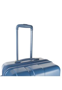 Maleta de dureza azul con un acabado texturizado, que cuenta con un asa superior y un asa retráctil para un transporte fácil. Cierre de cremallera visible.