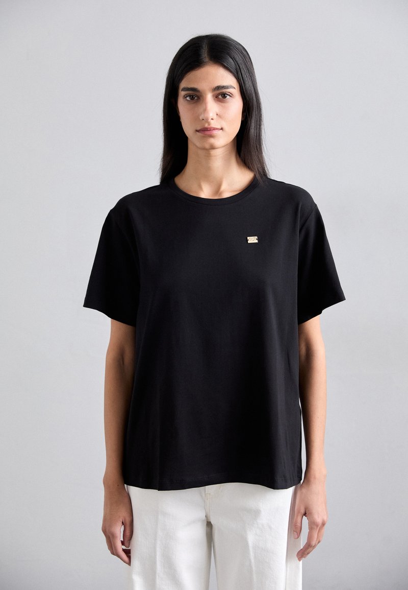 Black short-sleeve t-shirt made of cotton, featuring a round neckline and a small gold logo accent on the chest. Simple, straight-cut design.