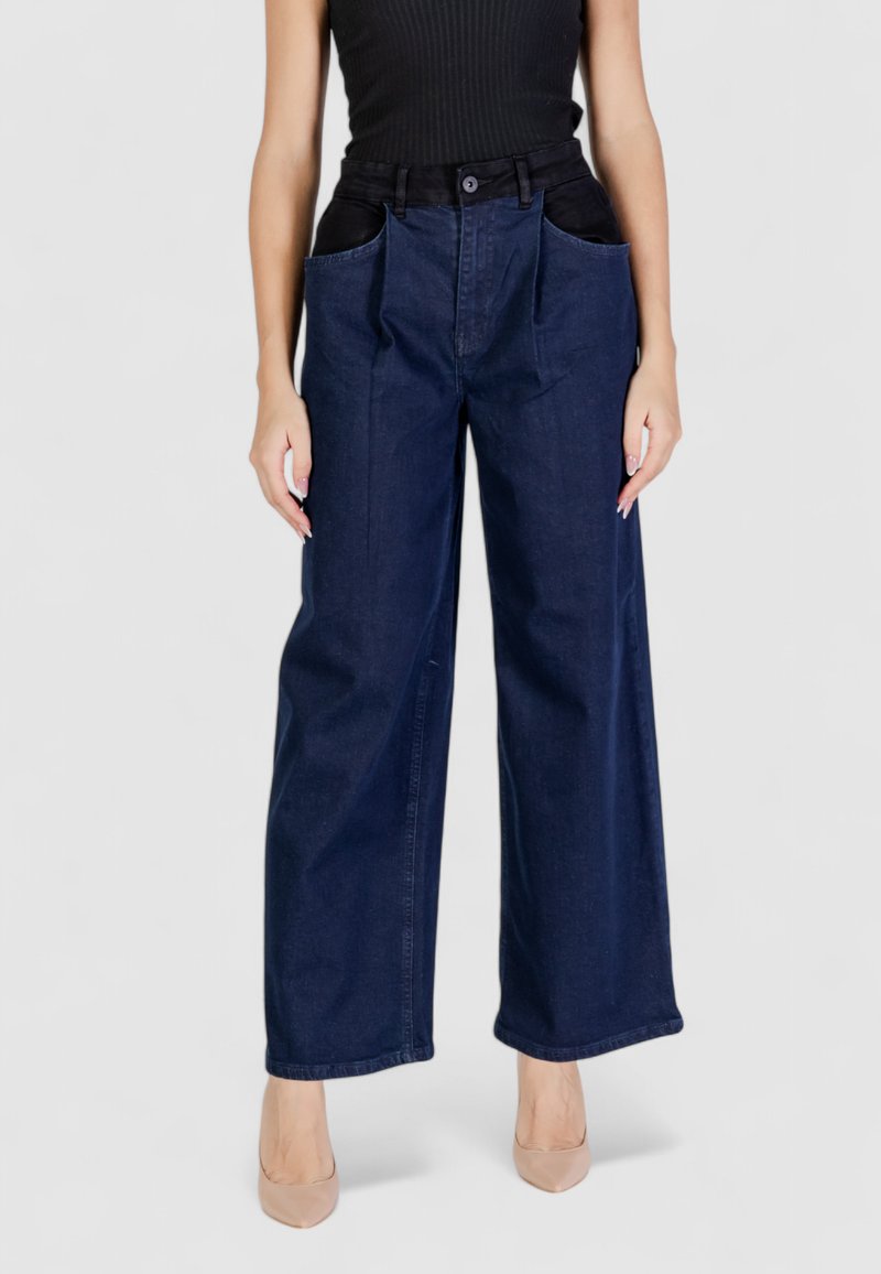 Jeans in denim scuro a gamba larga con ampie tasche anteriori nere, taglio dritto e tessuto non elasticizzato. La cintura è dotata di passanti per la cintura.