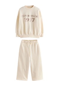 Sweat-shirt en polaire couleur crème avec imprimé "COPENHAGEN 1997", associé à un pantalon assorti à taille élastique, doté de poches latérales et de jambes larges.