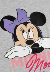 T-shirt grigia con una grande grafica di un personaggio dei cartoni animati con orecchie nere, fiocco viola e guanti bianchi, accompagnata da testo rosa.