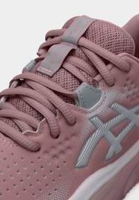 Ροζ αθλητικό παπούτσι με πλέγμα στο πάνω μέρος, επενδεδυμένη γλώσσα και γκρι λεπτομέρειες. Διαθέτει υφή στο πλευρικό λογότυπο και διάτρητες λεπτομέρειες για καλύτερο αερισμό.