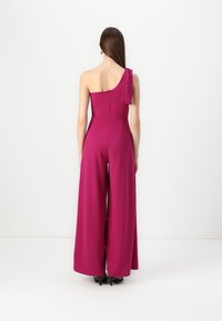 Magenta, én-skulder jumpsuit med en knyttet aksent på skulderen, tettsittende liv, og vide bukser; glatt tekstur med glidelåsfront.