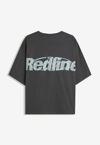 Siva oversize majica iz bombaža s okroglim izrezom. Na hrbtni strani ima izrazit napis "Redline" v svetlo modri in sivi barvi. Gladka tekstura.