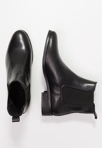 Černé kožené kotníkové boty s elastickými bočními panely, kulatou špičkou a nízkým podpatkem. Hladký povrch a minimalistický design.