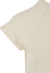 Ribbed short-sleeve top in light beige featuring a fitted design and contrasting flat seams, highlighting texture and contouring.