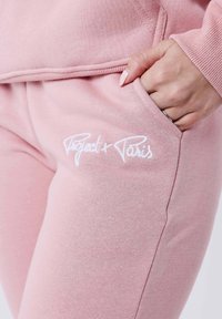Felpa rosa chiaro con una superficie testurizzata, caratterizzata da un logo ricamato bianco "Project x Paris" nell'area della tasca.