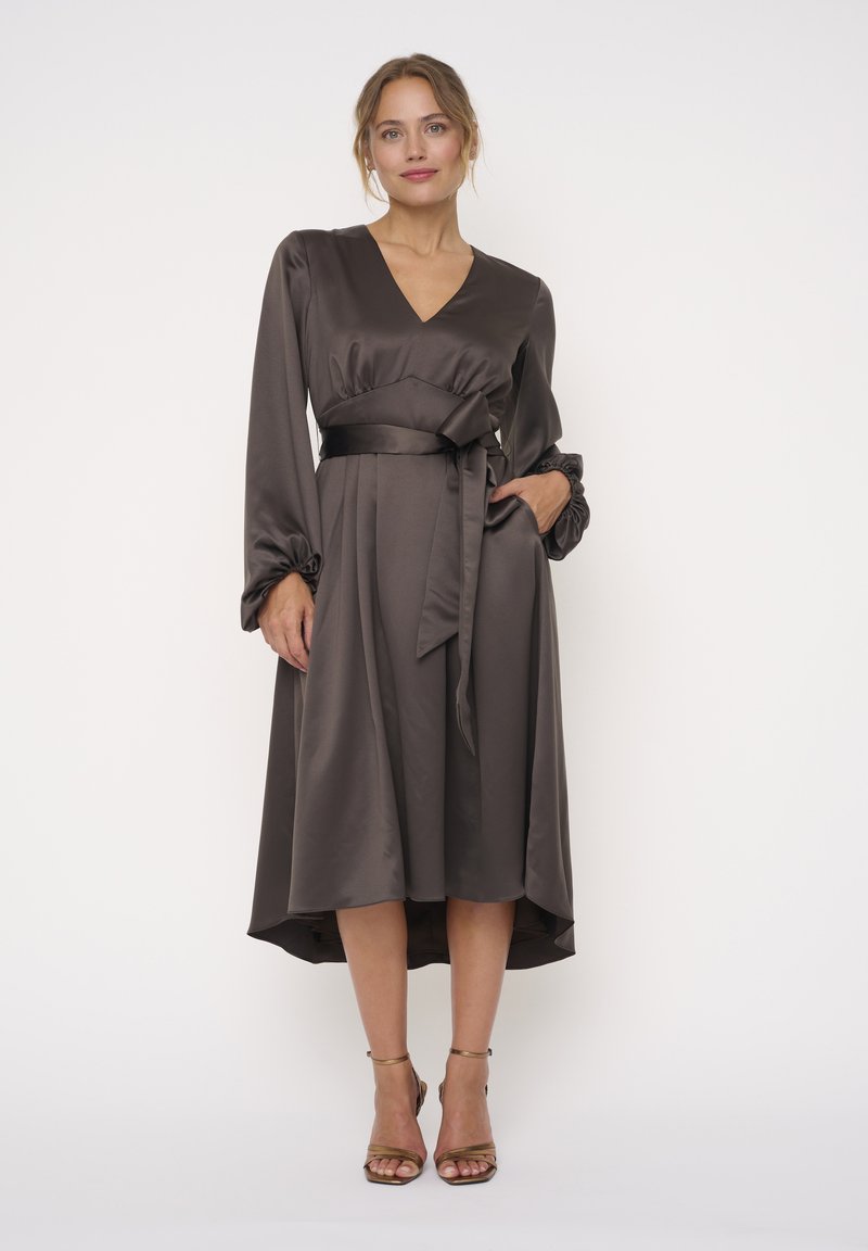 Braunes Satin-Kleid mit V-Ausschnitt, langen Ärmeln und Taillengürtel. Mit gerafften Manschetten und einem asymmetrischen Saumdesign.