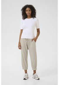 White, short-sleeve top with a ribbed texture paired with loose, light beige pants with an elastic waistband, finished with elastic cuffs.