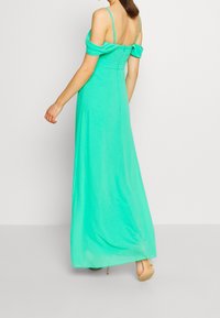 Pitkä, mintunvihreä mekko, jossa on off-the-shoulder-hihat, takana vetoketju ja liikkuva kangas, jossa on hoikka istuvuus ja lattiaan ulottuva malli.