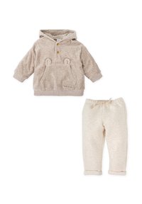 Sudadera beige con orejas de oso, bolsillo frontal y dos botones. Pantalones de quilt ligero beige a juego con cintura elástica y puños remangados.