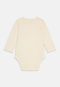 Beżowe body z długim rękawem wykonane z bawełny, z okrągłym dekoltem, miękką fakturą oraz dopasowanym krojem zapewniającym komfort. Widok od tyłu bez grafik.