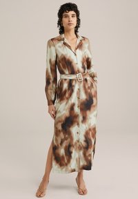 Dolga obleka s gumbi iz lahkega materiala. Ima zeleni, rjavi in kremni tie-dye vzorec, dolge rokave in pas, ki se ga da zavezati.