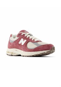 Red suede and mesh sneaker with beige accents, featuring a white "N" logo, textured rubber sole, and flat laces. Designed for comfort and support.