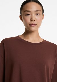 Donkerbruin, katoenen top met lange mouwen en een ronde hals, in een ontspannen pasvorm, met een gladde, licht gestructureerde oppervlakte.
