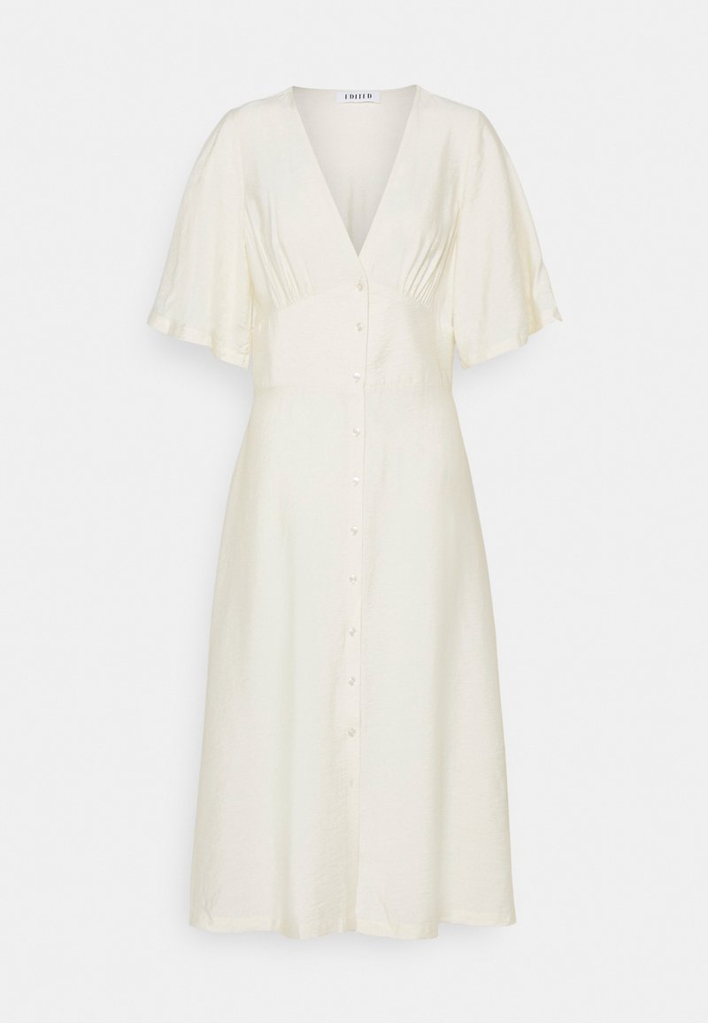 Robe en lin couleur crème avec un col en V, des manches courtes volantées et un devant boutonné. Elle présente un corsage ajusté et une jupe fluide.