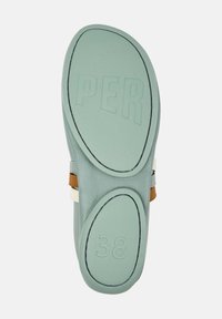Suela de zapato verde menta con superficie texturizada y texto en relieve "PER" y tamaño "38". Presenta acentos curvados y detalles de correas en contraste.