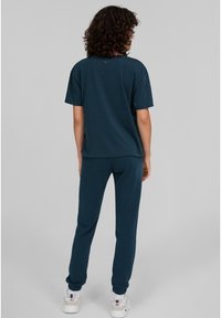 Camiseta azul marino y pantalones jogger a juego, hechos de algodón suave, con un corte relajado, mangas cortas y puños elásticos.