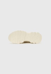 Sole of a light beige sneaker with thick, textured rubber tread pattern designed for traction and durability.